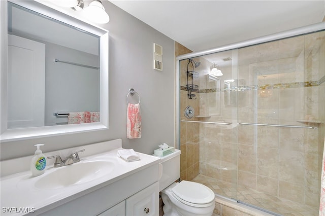 bathroom featuring vanity, toilet, and a shower with shower door