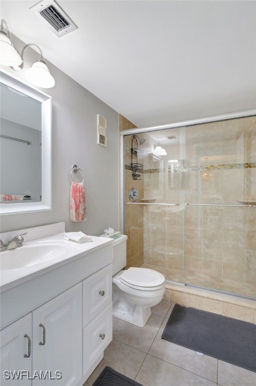 bathroom featuring tile patterned flooring, vanity, toilet, and walk in shower