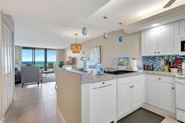 kitchen featuring white appliances, sink, kitchen peninsula, decorative backsplash, and white cabinetry