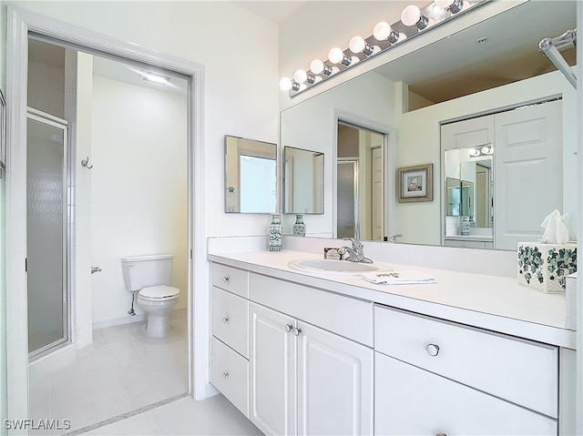 bathroom with tile patterned floors, vanity, toilet, and a shower with door