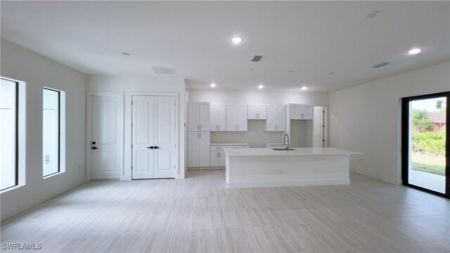 kitchen featuring sink, a center island with sink, and white cabinets