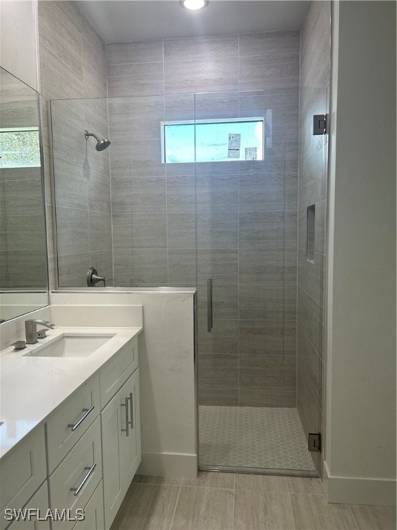 bathroom featuring a shower with door and vanity