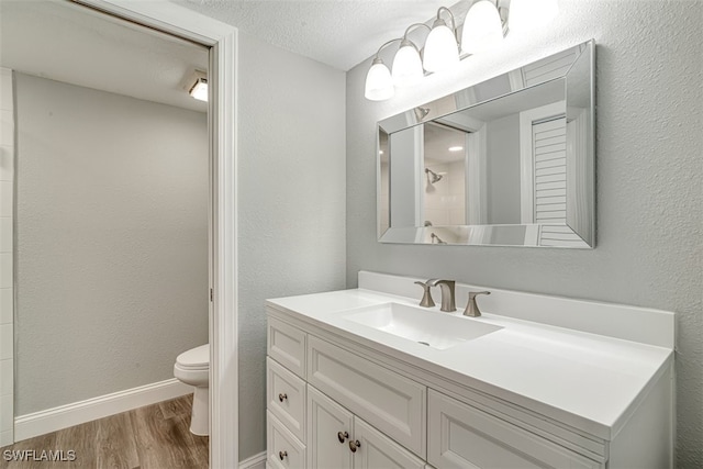 bathroom with a textured ceiling, hardwood / wood-style floors, vanity, a shower, and toilet