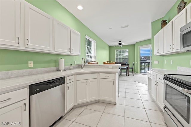 kitchen featuring white cabinetry, appliances with stainless steel finishes, light tile patterned floors, sink, and kitchen peninsula