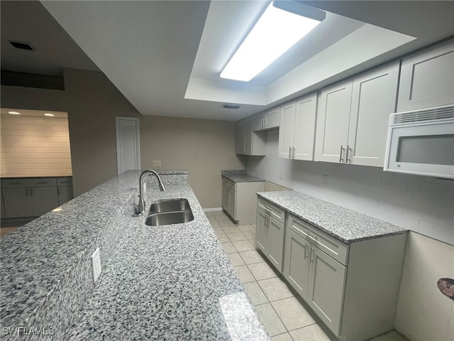 kitchen featuring light tile patterned flooring, sink, tasteful backsplash, and light stone countertops