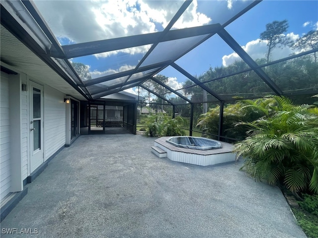 view of patio with a hot tub and glass enclosure