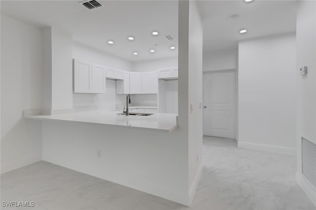 kitchen with kitchen peninsula, sink, and white cabinets