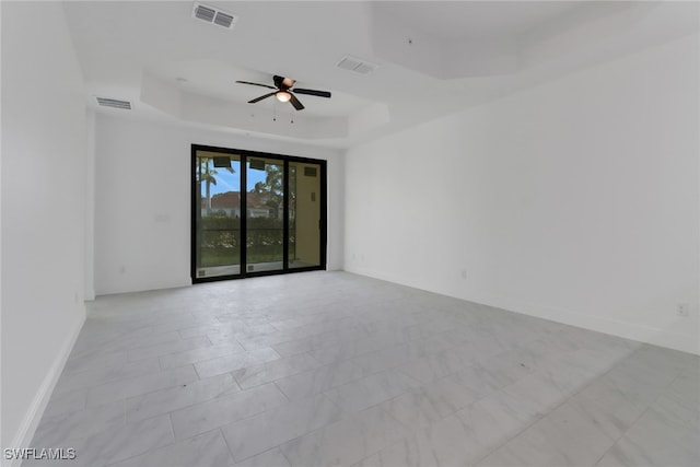 spare room with ceiling fan and a raised ceiling