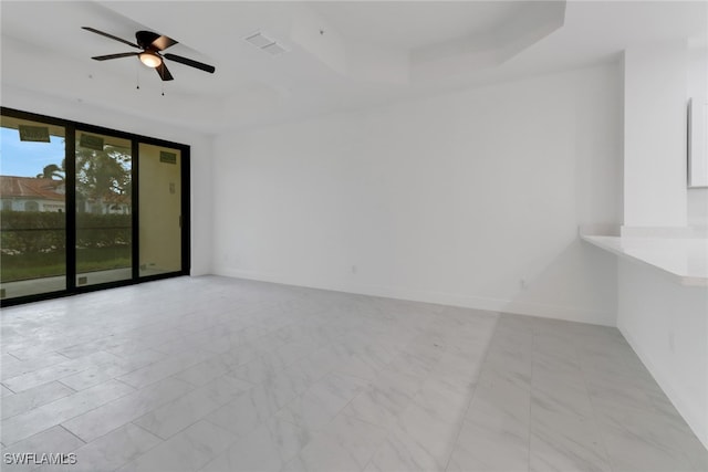 empty room featuring ceiling fan and a raised ceiling