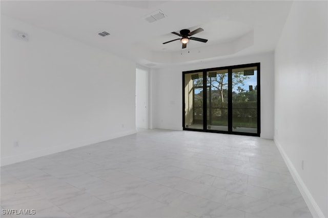 unfurnished room featuring a raised ceiling and ceiling fan