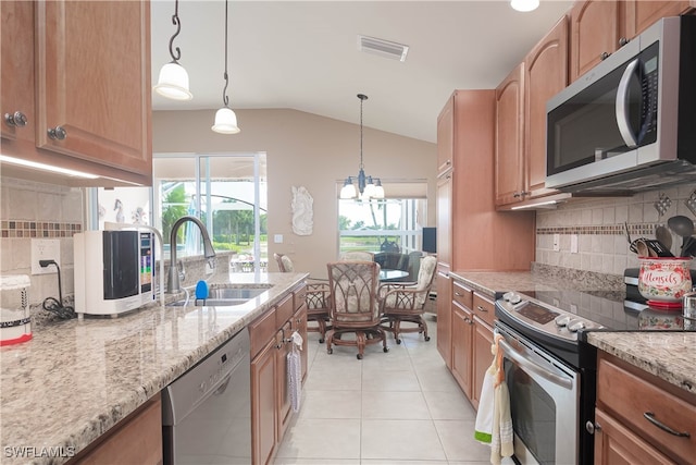 kitchen featuring lofted ceiling, decorative light fixtures, sink, stainless steel appliances, and light stone counters