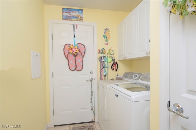 laundry room with light tile patterned floors, separate washer and dryer, and cabinets