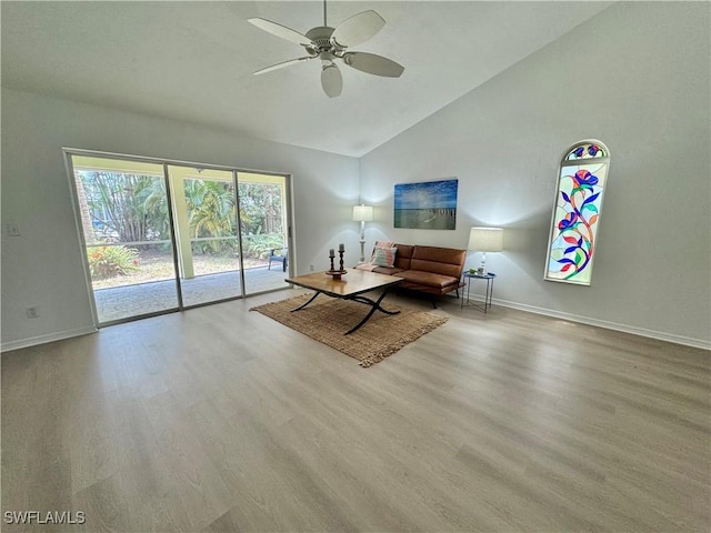 living area featuring a ceiling fan, wood finished floors, baseboards, and high vaulted ceiling