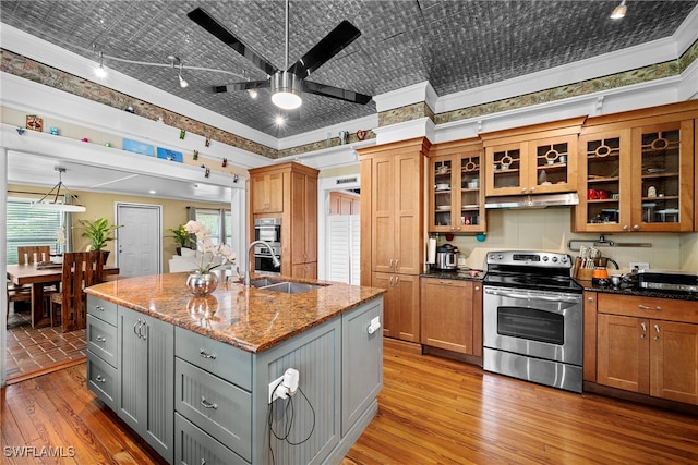 kitchen with light stone counters, appliances with stainless steel finishes, an island with sink, crown molding, and gray cabinets