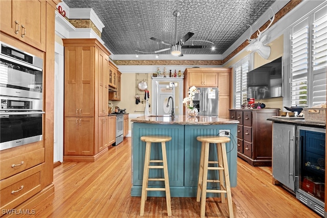 kitchen featuring a breakfast bar area, a kitchen island, appliances with stainless steel finishes, and light hardwood / wood-style flooring