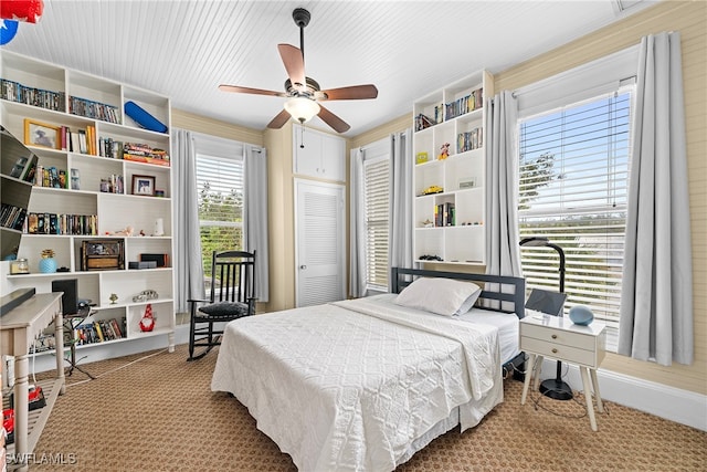 carpeted bedroom featuring multiple windows, ceiling fan, and a closet