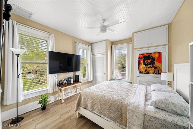 bedroom featuring multiple windows, light hardwood / wood-style flooring, ceiling fan, and a closet