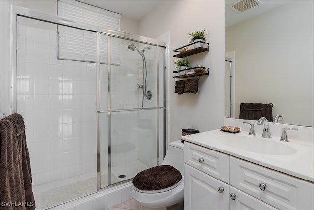 bathroom with a shower with shower door, vanity, toilet, and tile patterned floors