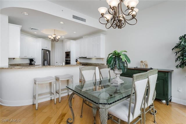 dining space with light wood-type flooring and a notable chandelier