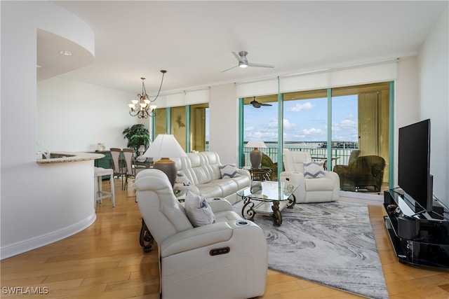 living room featuring ceiling fan with notable chandelier and light hardwood / wood-style flooring