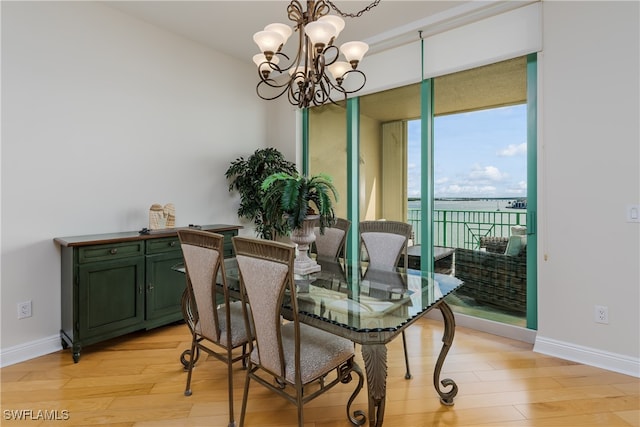 dining area with expansive windows, light wood-type flooring, and an inviting chandelier