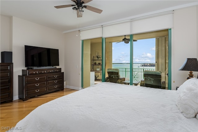 bedroom with access to outside, light hardwood / wood-style flooring, a water view, and ceiling fan