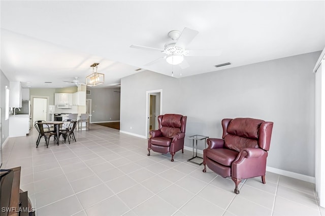 living area featuring ceiling fan, light tile patterned floors, and sink