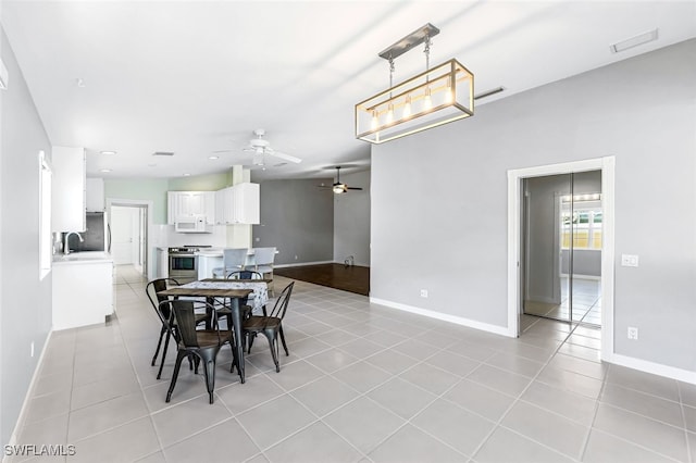 tiled dining space with ceiling fan and sink