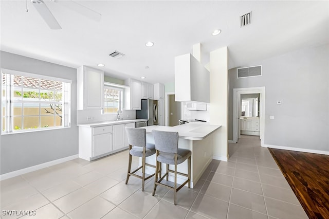 kitchen featuring white cabinetry, a breakfast bar, light tile patterned flooring, and stainless steel refrigerator