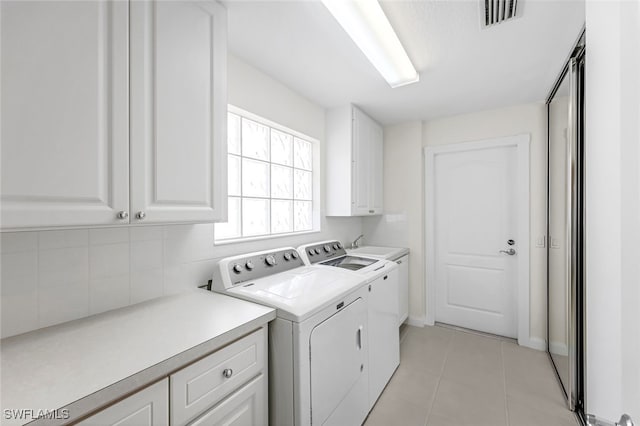 washroom featuring cabinets, separate washer and dryer, and light tile patterned floors