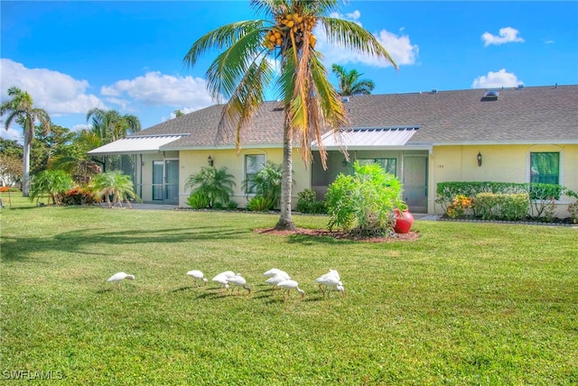 back of house featuring a lawn and a sunroom