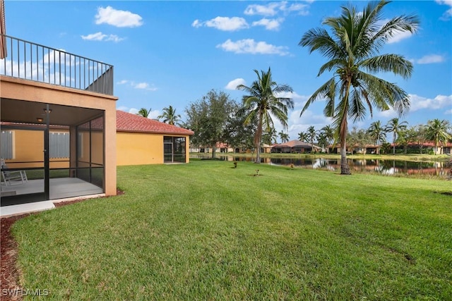 view of yard featuring a sunroom, a water view, and a balcony