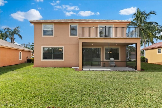 rear view of house with a patio area, a balcony, and a yard