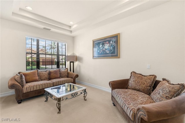 living room with a raised ceiling and light carpet