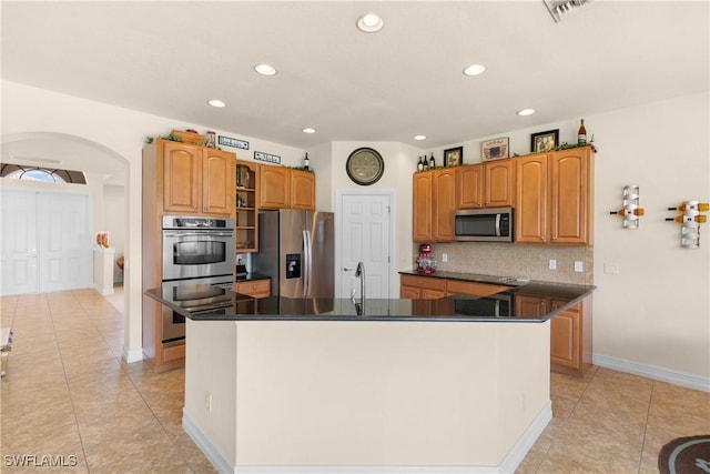 kitchen with a center island with sink, sink, decorative backsplash, light tile patterned flooring, and stainless steel appliances