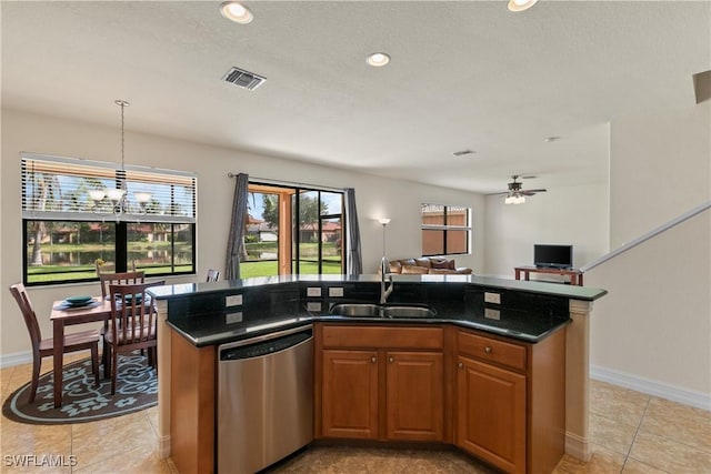 kitchen with sink, stainless steel dishwasher, dark stone counters, a kitchen island with sink, and ceiling fan with notable chandelier