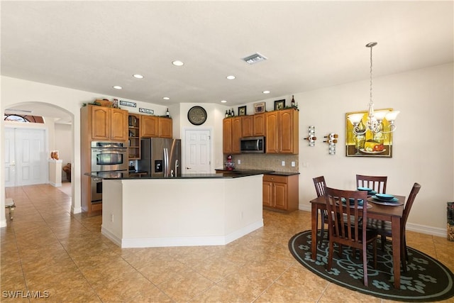 kitchen with tasteful backsplash, a notable chandelier, decorative light fixtures, a kitchen island, and appliances with stainless steel finishes