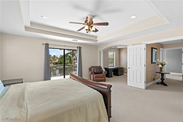 bedroom with ceiling fan, light colored carpet, and a tray ceiling