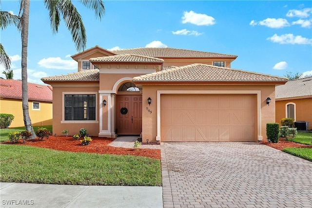 mediterranean / spanish-style home with a garage, central AC unit, and a front yard