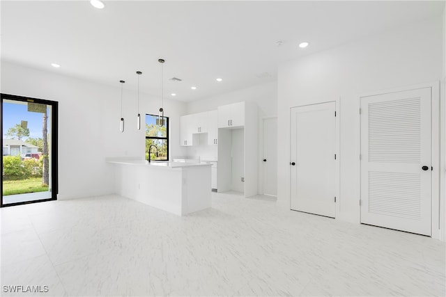 interior space with white cabinets, kitchen peninsula, sink, and pendant lighting