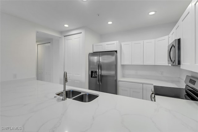 kitchen featuring light stone counters, sink, white cabinets, and stainless steel appliances