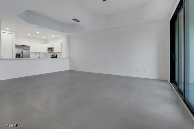 unfurnished living room featuring a tray ceiling and sink