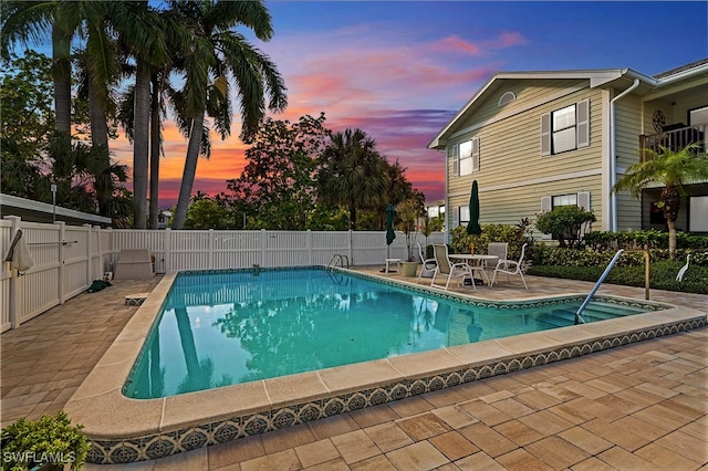 pool at dusk featuring a patio