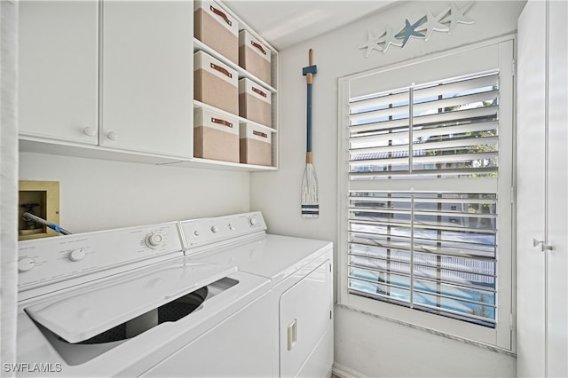 clothes washing area with cabinets and separate washer and dryer