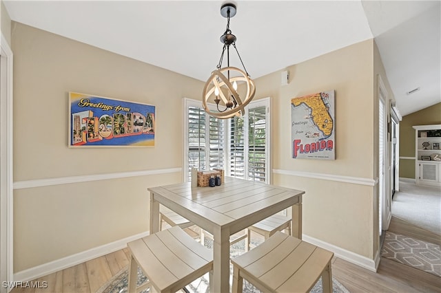 dining room featuring a chandelier, hardwood / wood-style floors, and vaulted ceiling