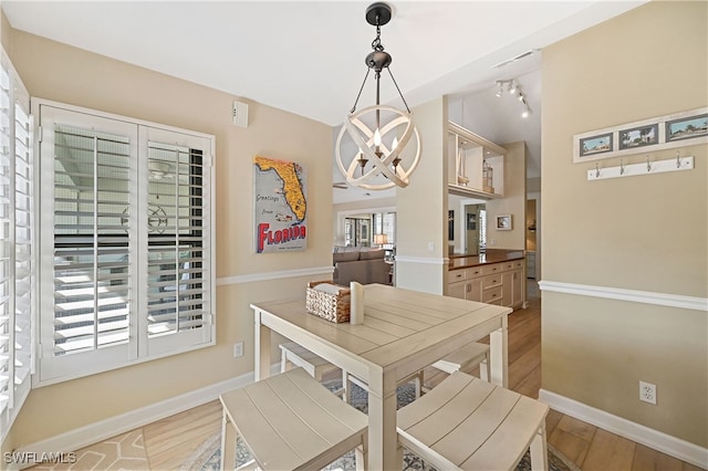 dining area featuring light hardwood / wood-style floors, a chandelier, and track lighting