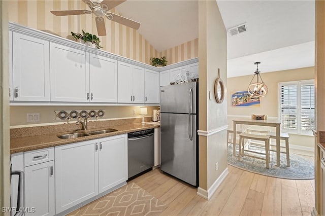 kitchen featuring white cabinets, appliances with stainless steel finishes, vaulted ceiling, and light hardwood / wood-style flooring