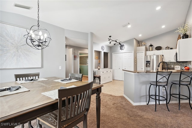 carpeted dining area with a chandelier, lofted ceiling, and sink