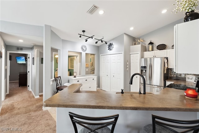 kitchen featuring stainless steel fridge with ice dispenser, light carpet, kitchen peninsula, and a breakfast bar area