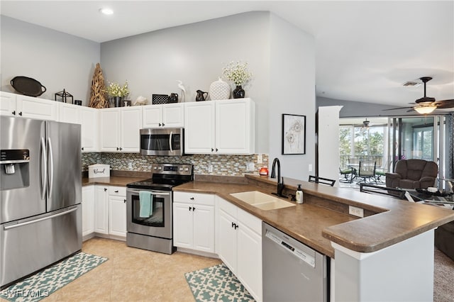 kitchen with white cabinets, kitchen peninsula, appliances with stainless steel finishes, and sink